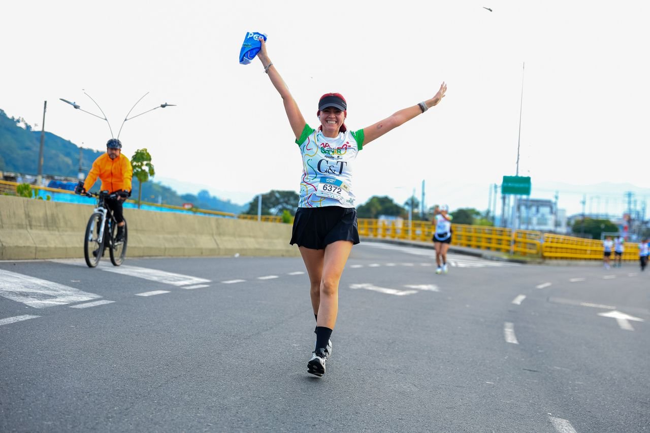 Happy female runner celebrates during a marathon outdoors on a road course.